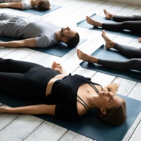 Groupe de personnes se reposant après une séance de yoga allongée